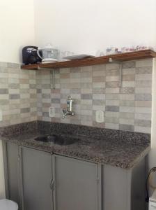 a kitchen counter with a sink and tiles on the wall at By Búzios Loft in Búzios