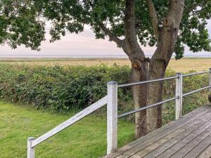 a wooden boardwalk next to a tree with a fence at 10 person holiday home in R m in Bolilmark