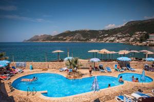 a swimming pool next to the ocean with chairs and umbrellas at David Lux beach rooms in Dobra Voda