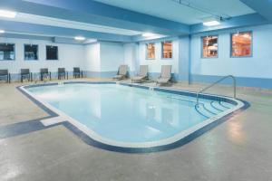 a large swimming pool in a room with chairs and tables at Super 8 by Wyndham Fort Saskatchewan in Fort Saskatchewan