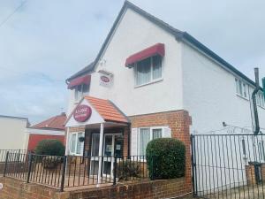 a white house with a fence in front of it at AJ Lodge in Slough