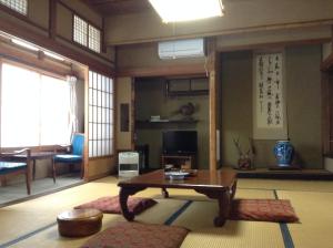 a living room with a table in a room at Chitosekan in Nozawa Onsen