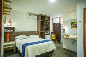 um quarto com uma cama e uma casa de banho com um lavatório em SEGUNDA CASA - Seu cantinho em Guarapari, 1 minuto a pé da Praia do Morro! Suítes confortáveis e modernas - Para casal ou para grupos de até 5 pessoas em Guarapari