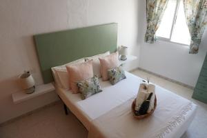 a white bed with pillows and a basket on it at Los Trigos, Casa Rural in Montejaque