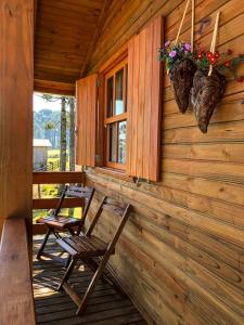 2 sillas en el porche de una cabaña de madera en Pousada Chales Aconchego Serrano en Bom Jardim da Serra