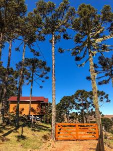 um portão de madeira em frente a uma casa com árvores em Pousada Chales Aconchego Serrano em Bom Jardim da Serra