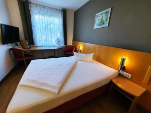 Schlafzimmer mit einem großen weißen Bett und einem Schreibtisch in der Unterkunft Hotel SunParc - SHUTTLE zum Europa-Park Rust 4km & Rulantica 2km in Ringsheim