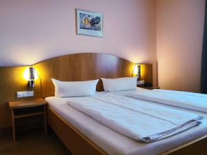 Bett in einem Hotelzimmer mit 2 weißen Betten in der Unterkunft Hotel SunParc - SHUTTLE zum Europa-Park Rust 4km & Rulantica 2km in Ringsheim