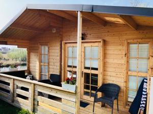 eine Holzhütte mit einem Dach und Stühlen auf einer Terrasse in der Unterkunft STAŁY LĄD in Ustronie Morskie