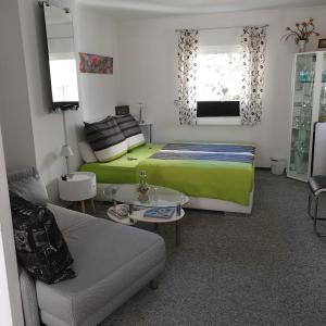 een slaapkamer met een groen bed en een bank bij Ferienapartment MOHNBLUME in Eichwalde