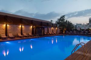 una gran piscina con sillas y un edificio en Athineon Hotel en Rodas