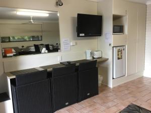 a kitchen with black cabinets and a tv on the wall at Golden Palms Motor Inn in Bundaberg