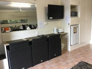 a kitchen with a counter with a refrigerator and a tv at Golden Palms Motor Inn in Bundaberg