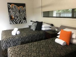 a bed with two pillows and a painting on the wall at Golden Palms Motor Inn in Bundaberg
