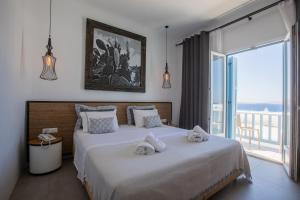 a bedroom with two beds and a large window at Harmony Boutique Hotel in Mýkonos City