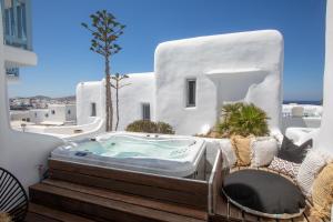 a jacuzzi tub on a balcony with white buildings at Harmony Boutique Hotel in Mikonos