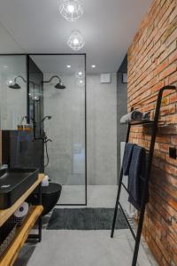 a bathroom with a black sink and a brick wall at Apartamenty Colobrzeg Loft in Kołobrzeg