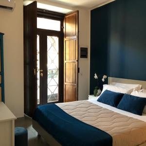 ein Schlafzimmer mit einem großen Bett mit blauer Bettwäsche und einer Tür in der Unterkunft CIVITAS 2 in Catania
