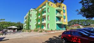 a green building with cars parked in front of it at Guesthouse Kamelia in Ahtopol