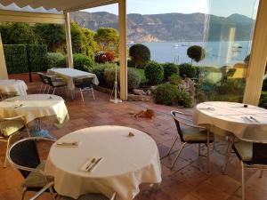 a restaurant with tables and chairs with a view of the ocean at Hôtel de Charme Brise Marine in Saint-Jean-Cap-Ferrat