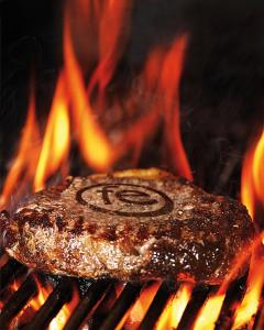 a steak on a grill with fire in the background at feRUS Hotel in Lucerne