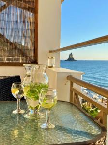 3 Gläser Wein auf einem Tisch mit dem Meer in der Unterkunft Nereides Apartments in Agios Gordios