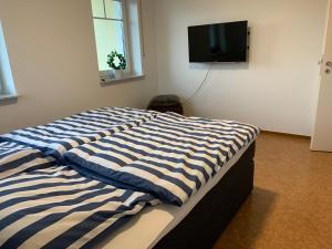 ein Bett mit einer blau-weißen gestreiften Decke in einem Zimmer in der Unterkunft Ferienoberwohnung in Villa Pesca in Cloppenburg