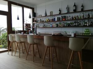 a bar with white chairs and a counter with bottles at Hotel Llorca in Platja de l’Almadrava