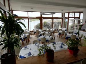 a restaurant with white tables and chairs and potted plants at Hotel Llorca in Platja de l’Almadrava
