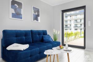 niebieska kanapa w salonie z oknem w obiekcie Apartament Seaside View tuż przy plaży- Gardenia Seaside Dziwnów-SANNEL Apartments for rent w Dziwnowie