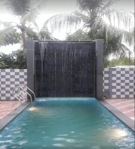 uma piscina com uma fonte de água e uma cascata em La Villa Beach Paradise em Mahabalipuram