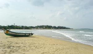 - un bateau assis sur une plage au bord de l'océan dans l'établissement La Villa Beach Paradise, à Mahabalipuram