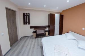 a bedroom with a white bed and a desk at Casa Andy in Buşteni
