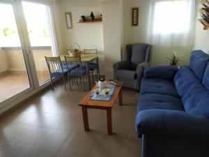ein Wohnzimmer mit einem blauen Sofa und einem Tisch in der Unterkunft Primera linea de playa Punta del Moral El Espigon in Ayamonte