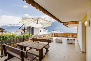 eine Terrasse mit einem Holztisch und einem Sonnenschirm in der Unterkunft Ferienwohnungen Ortlerblick in Mals im Vinschgau