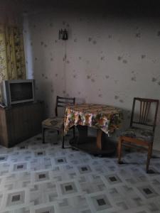 Cette chambre dispose de 2 chaises, d'une table et d'une télévision. dans l'établissement Вишня,двокімнатна квартира, à Trouskavets