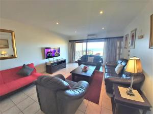 sala de estar con muebles de cuero y sofá rojo en Kuta Beach A en Ramsgate