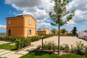 ein gelbes Haus und ein Baum im Hof in der Unterkunft Sul Calar del Sole al Conero in Recanati