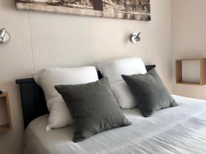 Una cama con cuatro almohadas encima. en Residence Soleil des Thermes 2, en Le Mont-Dore