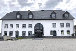 een groot wit gebouw met een zwart dak bij POSTRELAIS ARDENNES "Belle-Vue" in Burg-Reuland