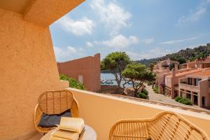 balcón con sillas de mimbre y vistas al agua en Hotel Cala Lunga, en La Maddalena