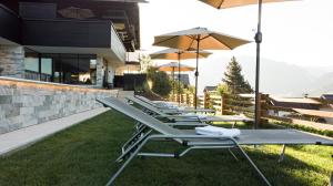 une rangée de chaises longues avec des parasols sur l'herbe dans l'établissement Sonnhof by Vitus Winkler, à Sankt Veit im Pongau