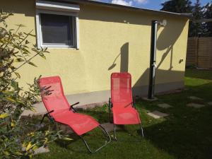 due sedie rosse sedute sull'erba di fronte a una casa di Am Schwielochsee1 a Schwielochsee