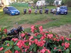 a group of motorcycles parked in a yard with flowers at Aruvi Hotel in Yelagiri