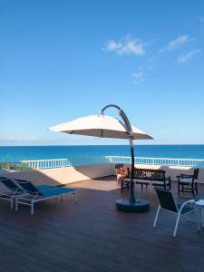 a patio with chairs and an umbrella and the ocean at Hotel Llorca in Platja de l’Almadrava