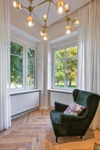 d'un salon avec une chaise verte et des fenêtres. dans l'établissement Apartman Otokar, à Osijek