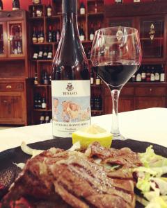 a bottle of wine and a plate of meat and a glass at Hotel Scrivano in Randazzo