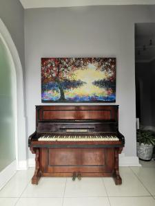 a piano in a room with a painting on the wall at Dawson Manor Guest House in East London