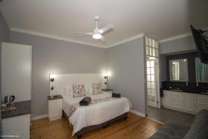 a white bedroom with a bed and a ceiling fan at Dawson Manor Guest House in East London