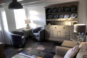 a living room with blue chairs and plates on a wall at Bojewyan Cottage, Sandy Beaches and Great walking in Penzance